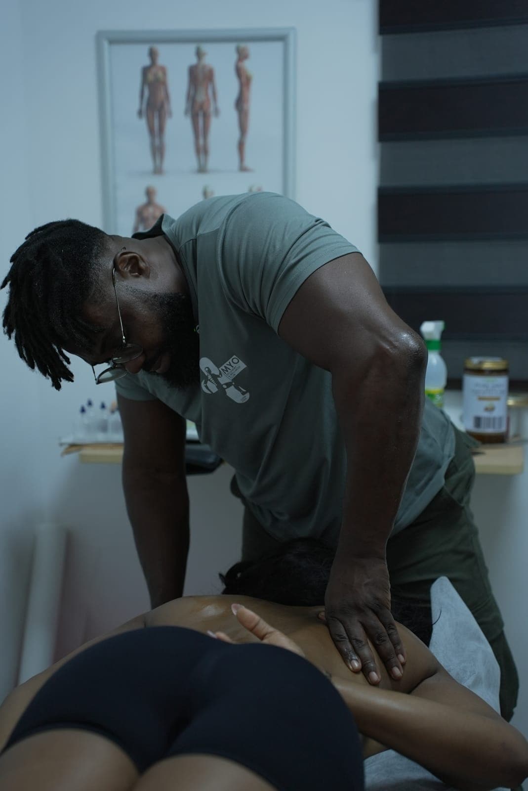 A MYO therapist working both hands into a client's upper back in the treatment room
