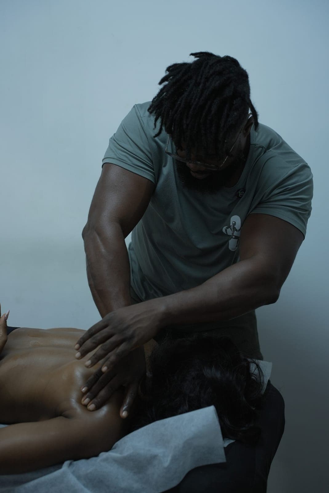 A MYO therapist working both hands across a client's shoulders against a plain wall