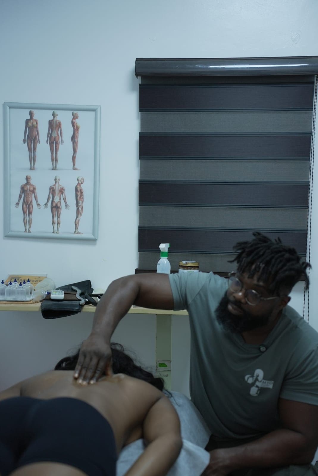 A MYO therapist seated beside the treatment couch, one hand working along a client's upper back